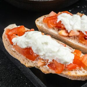 Crusty Bruschettas toasts with stracciatella cheese, chopped tomatoes and thyme.